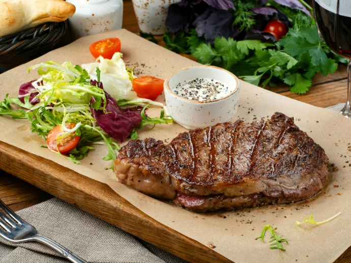 a steak with a side of salad and a glass of wine